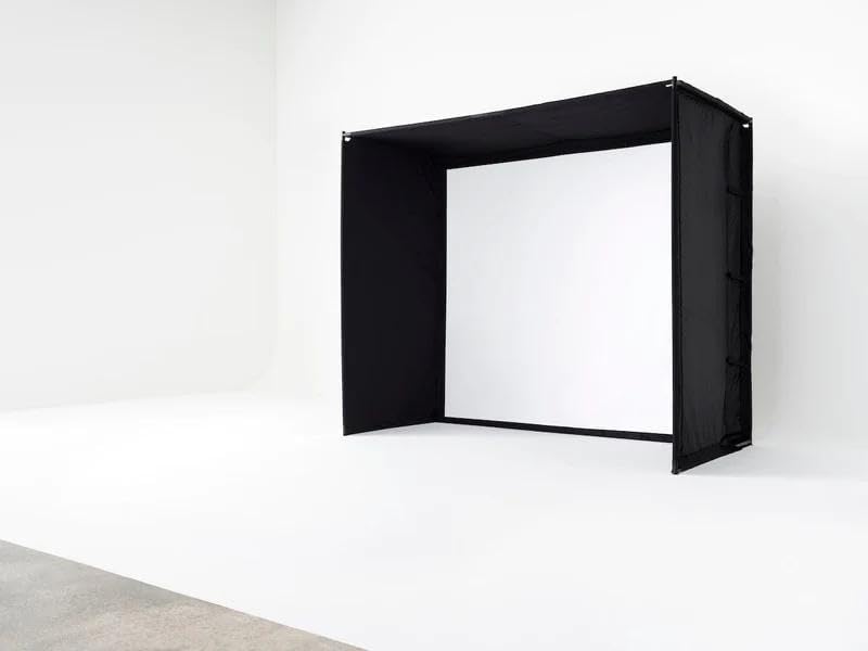 Golf simulator enclosure with black side panels and a white impact screen.